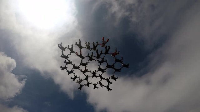 Large group of skydivers coming together in freefall, moving into a coordinated formation