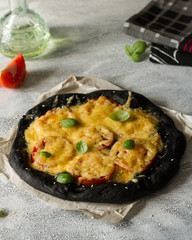 Black dough pizza with tomatoes and cheese.