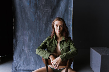 Portrait of a young woman in underwear and in a denim jacket in the studio.