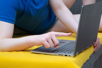 Fototapeta premium A man is sitting on the sofa at a laptop. Engaged in work on deleting over the Internet.
