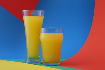 Glasses of orange juice  on a colorful background
