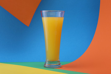 Glasses of orange juice  on a colorful background