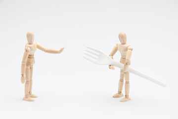 Wooden dummy refusing to help his friend to carry a biodegradable fork in front of a white background