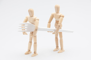 Wooden dummies carrying a biodegradable fork in front of a white background