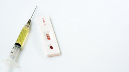 Rapid test kit for the coronary-19 virus, a vaccine contained in a syringe on a white background.