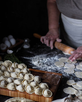 Grandma Cooks Dumplings On A Dark Table.