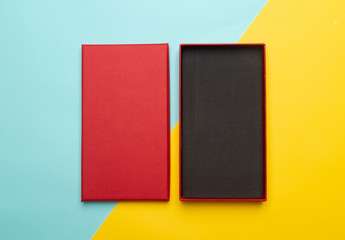 Red box product packaging isolated on yellow half blue background. Flat lay Top view.