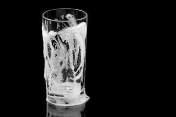 Empty glass with foam, clean glass with bubbles and drops isolated on black background