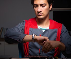 Young handsome repairman repairing computer