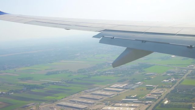 Commercial plane landing at Warsaw Frederic Chopin Airport. View from the window of the plane to the wing. The operation process of the air brakes and flaps on an airplane wing during landing.