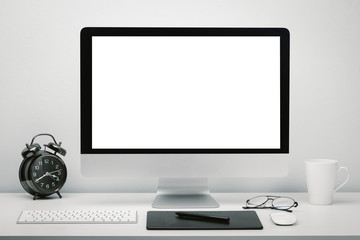 Stylish workspace with blank screen computer display for mockup on work desk with keyboard, mouse, cup of coffee, clock, eyeglasses and pen tablet.
