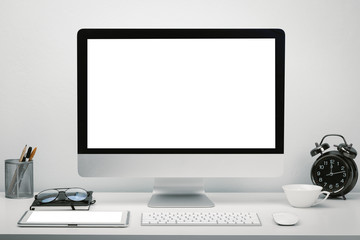 Stylish workspace with blank screen computer display and tablet for mockup on work desk with keyboard, mouse, clock, eyeglasses and stationery.