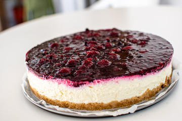Close up of a fresh cheesecake on a white surface.