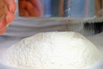 Woman' s hand sifting the flour.
