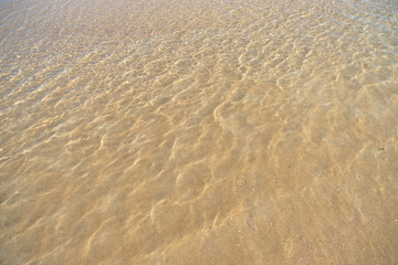 Fototapeta na wymiar Clear water on a sandbank on a sandy beach. Background of water surface.