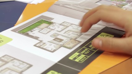 Israeli man looking at real estate information brochure. Close up on his hand. The hebrew words Dirot Emcha" (Mid apartments) or "Dirot Gag" (Roof apartments) are appears."