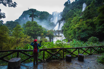 Fototapeta na wymiar The girl in blue sweater touring on Thi-Lo-Su waterfall, Beautiful waterfall in Tak province, ThaiLand.