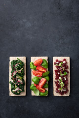 vegan sandwiches with spinach, nuts, tomatoes, basil, beets and micro greens on a black background. View from above.