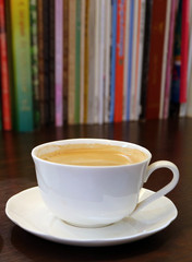 Vertical Image of a Cup of Hot Coffee with Blurry Book Shelf in Background