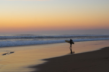 Naklejka premium Silhouette de surfeur face au coucher de soleil sur l'océan