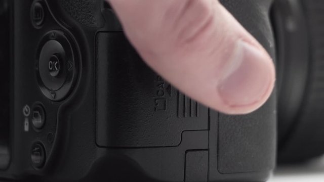 The hand removes and inserts the SD memory card in the camera.