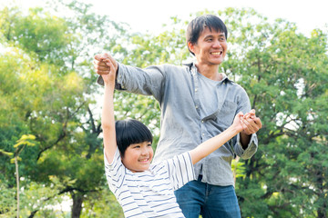 Portrait of happy Asian father playing with son, holding and raise his hand up to fly at park. dad support kid dream. family love living lifestyle insurance. learning and education together concept