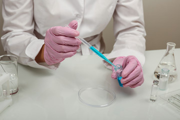 production of vaccine against virus . scientist's hands in gloves are conducting chemical...