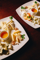 Stock Photo - Cheese plate: Emmental, Camembert, Parmesan, blue cheese, walnuts, hazelnuts, honey and apple