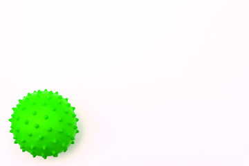 a small round ball with green pimples in the form of a koronavirus lies on a white background in the lower left corner