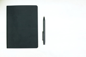a black diary and a black ballpoint pen lie on a white background
