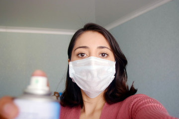 Young woman wearing face mask with disinfectant in hand 
