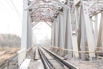 railway bridge over a small river, view of the railway tracks through the bridge arch, selective focus, tinted image