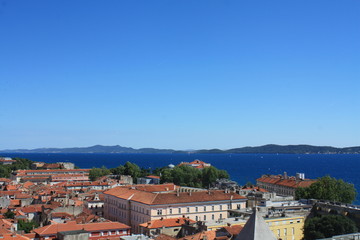 Fototapeta na wymiar Beautiful view of the rooftops of Zadar from above and the Adriatic Sea. The horizontal landscape of the European city, a clean and beautiful view of the red roofs from a bird's eye view.