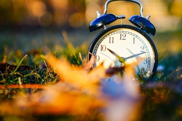 Image of spring Time Change. Summer back concept. Vintage alarm Clock outdoors. alarm clock on green grass 