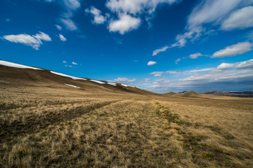 the snow has not yet completely melted on the mountains, clouds float across the sky and form shadow patterns on the mountains