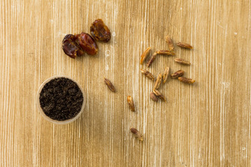 Top view of cup with soil, dates fruit and bones for planting palm on the wooden background