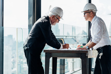Two industrial engineer wear safety helmet engineering working and talking with drawings inspection...