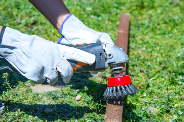 Removing rust and paint from an old metal pipe with a wire brush, closeup