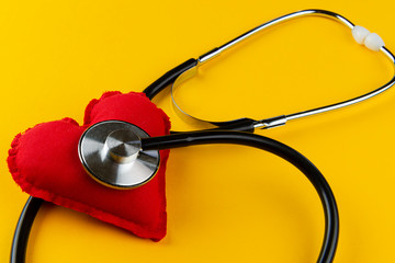 Red heart with stethoscope on yellow background. Cardiologist concept.