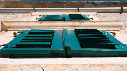 Old wooden blue green window of Mediterranean house - view from below.