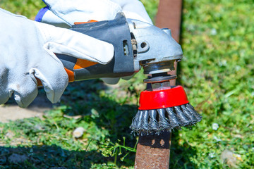 Заголовок: Removing rust and paint from an old metal pipe with a wire brush, closeup