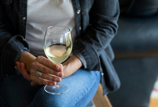 Young woman drinks a glass of white wine alone in her home