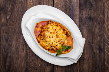 Tasty lasagne with meat covered with cheese served on white plate.