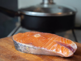salmon steak lies against the background of the kitchen