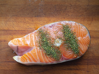 raw salmon Steak with spices on a wooden Board