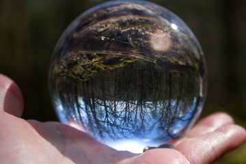 The crystal ball reflects the beautiful nature. The sphere is on the human palm.