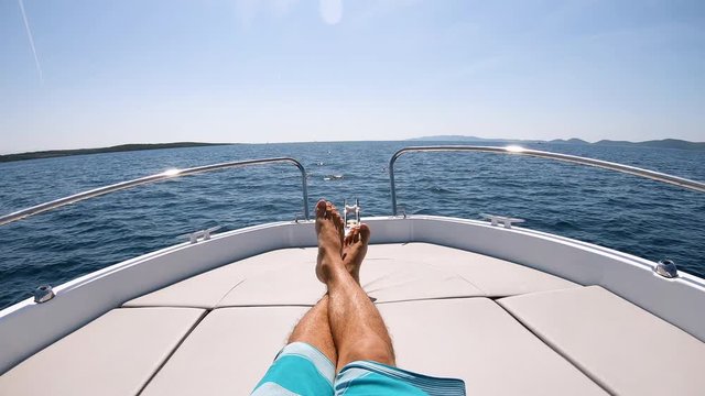 Young man chilling on a boat on sunny day and relaxing on nice waves