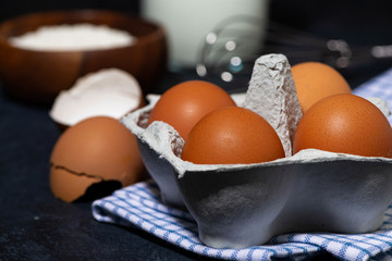 box with fresh eggs, flour, milk and a whisk, closeup