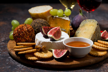 cheese, crackers and fruits, delicious wine snacks on dark background, closeup