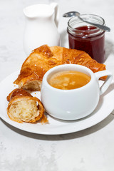 cup of espresso and fresh croissants, berry jam on white background, vertical